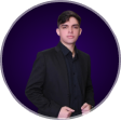 Foto de João Victor sério, usando blazer e fundo roxo